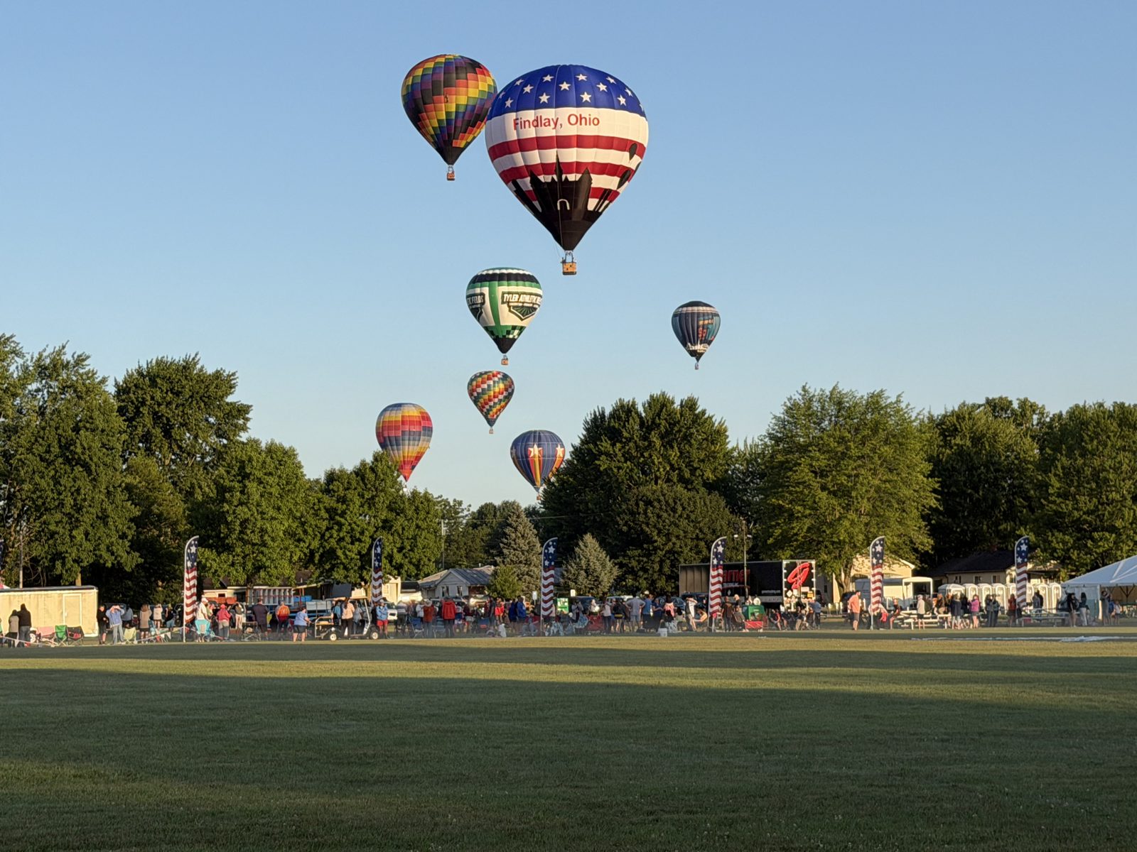 Balloons lifting off over a crowd at a balloon festival