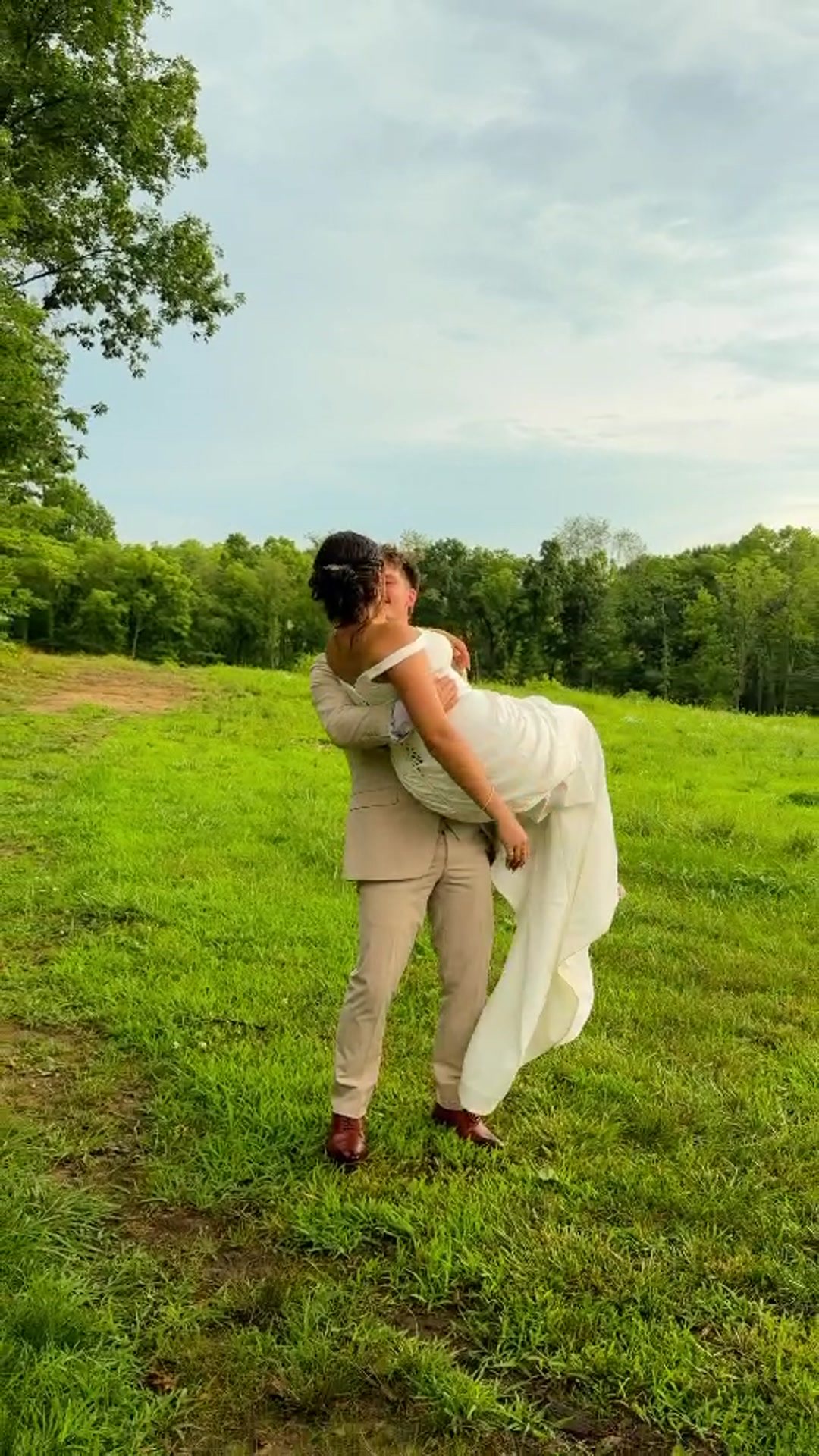 Groom carrying the bride through an open field